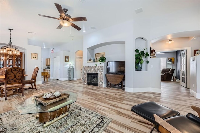 4361 Valley Quail Way N, Las Vegas, NV 89084 - living area featuring arched walkways, a ceiling fan, light wood finished floors, and a glass covered fireplace