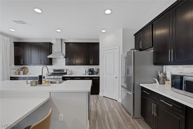 7890 S Miller Ln, Las Vegas, NV 89113 - kitchen featuring wall chimney range hood, appliances with stainless steel finishes, tasteful backsplash, light countertops, and light wood-style floors