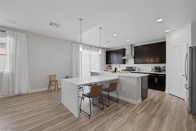 7890 S Miller Ln, Las Vegas, NV 89113 - kitchen featuring wall chimney range hood, freestanding refrigerator, light wood finished floors, an island with sink, and recessed lighting