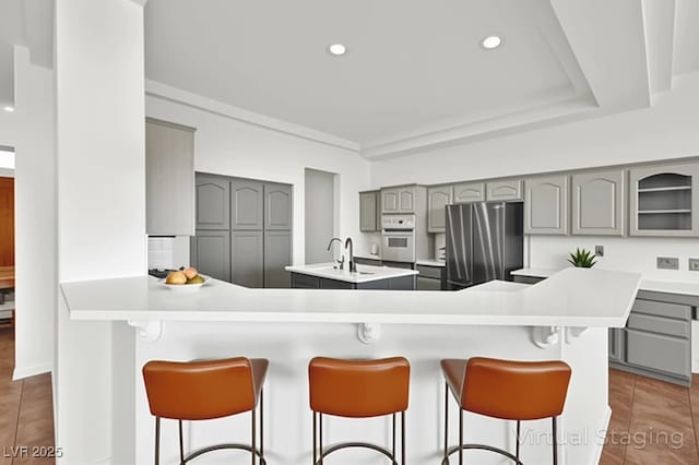 10920 Grand Haven Ave, Las Vegas, NV 89134 - kitchen featuring gray cabinets, freestanding refrigerator, white oven, an island with sink, and recessed lighting