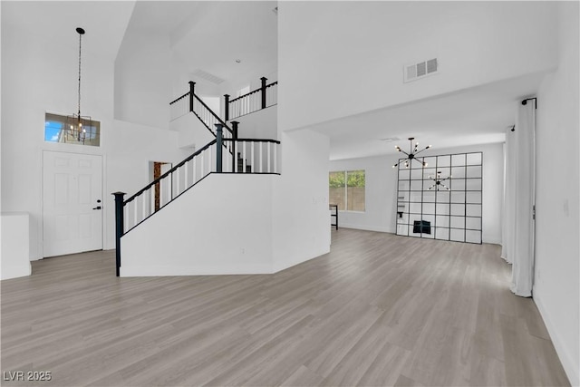 21 Rue De Degas, Henderson, NV 89074 - unfurnished living room with a chandelier, wood finished floors, a towering ceiling, and stairway
