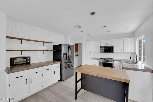 21 Rue De Degas, Henderson, NV 89074 - kitchen with appliances with stainless steel finishes, white cabinetry, open shelves, decorative backsplash, and light wood-style flooring
