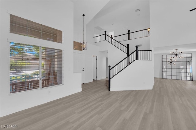 21 Rue De Degas, Henderson, NV 89074 - unfurnished living room with a chandelier, a high ceiling, light wood-style floors, and stairway