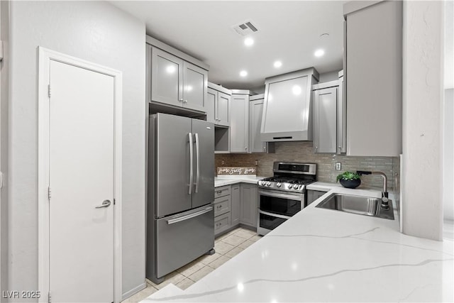 6635 Caporetto Ln Unit 204, North Las Vegas, NV 89084 - kitchen with appliances with stainless steel finishes, gray cabinetry, decorative backsplash, light stone countertops, and premium range hood