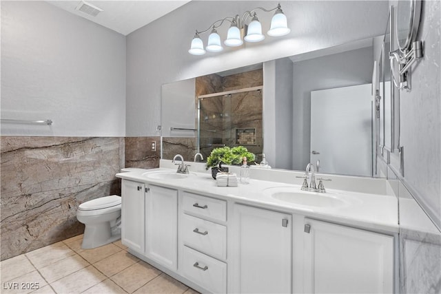 6635 Caporetto Ln Unit 204, North Las Vegas, NV 89084 - full bathroom with double vanity, a shower stall, tile walls, tile patterned floors, and a wainscoted wall