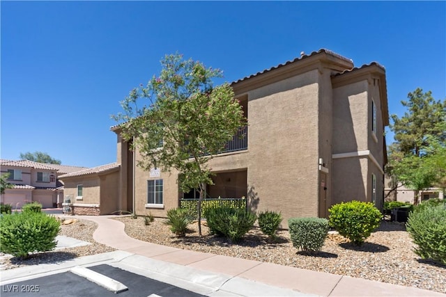 6635 Caporetto Ln Unit 204, North Las Vegas, NV 89084 - view of property exterior featuring stucco siding, uncovered parking, and a tile roof