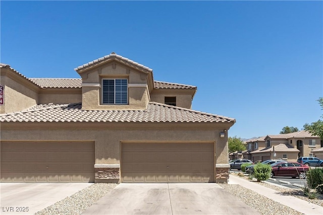 6635 Caporetto Ln Unit 204, North Las Vegas, NV 89084 - view of front of home with stucco siding, concrete driveway, a garage, a tile roof, and stone siding