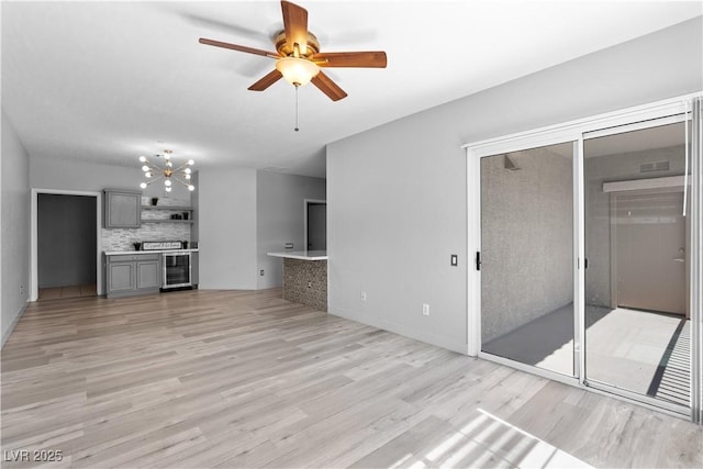 6635 Caporetto Ln Unit 204, North Las Vegas, NV 89084 - unfurnished living room with light wood-style floors, a ceiling fan, beverage cooler, and a chandelier