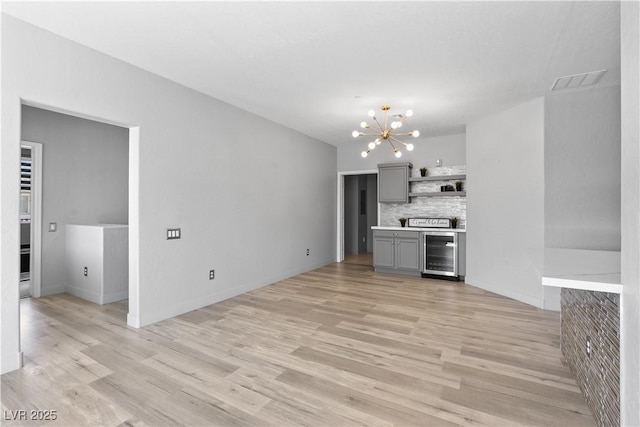 6635 Caporetto Ln Unit 204, North Las Vegas, NV 89084 - unfurnished living room with a chandelier, beverage cooler, and light wood-style floors