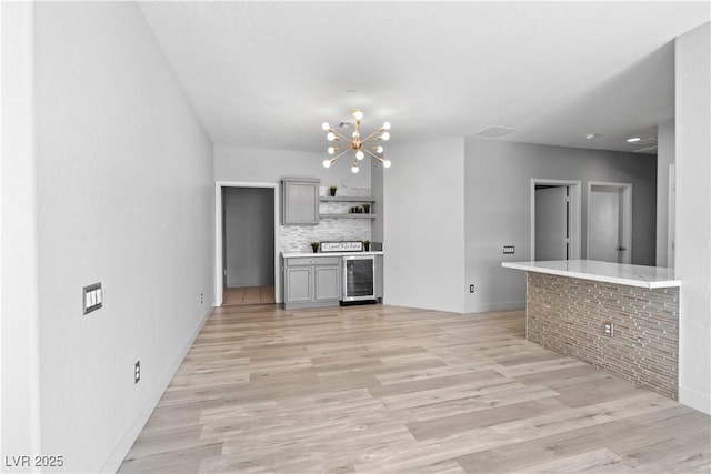 6635 Caporetto Ln Unit 204, North Las Vegas, NV 89084 - kitchen featuring wine cooler, light wood-style flooring, a chandelier, tasteful backsplash, and gray cabinets