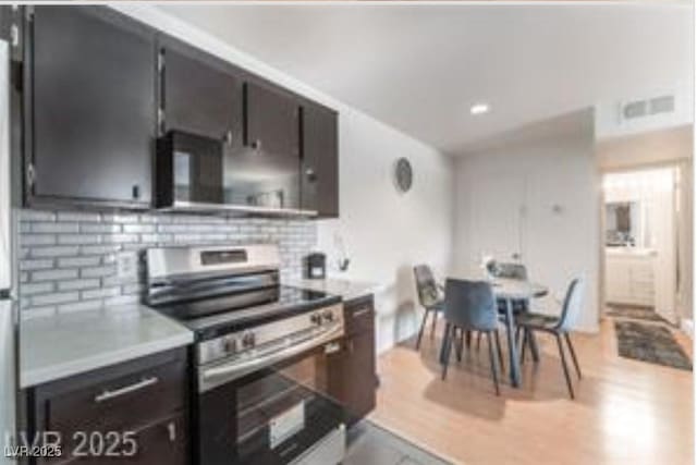 221 Mission Catalina Ln Unit 104, Las Vegas, NV 89107 - kitchen featuring stainless steel range with electric stovetop, backsplash, light countertops, light wood finished floors, and recessed lighting