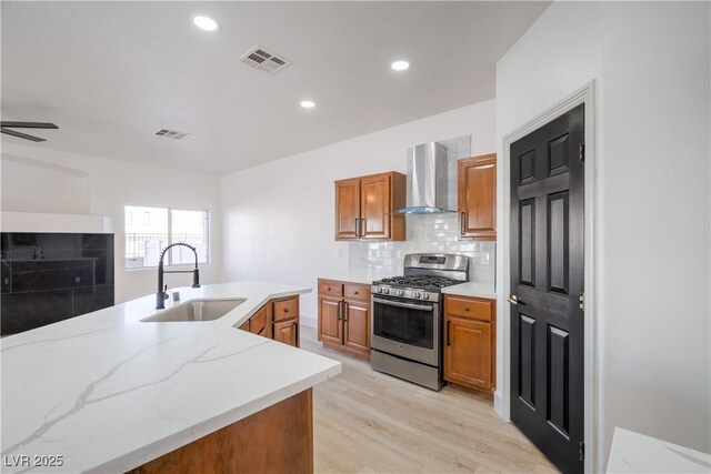 8798 Tom Noon Ave Unit 103, Las Vegas, NV 89178 - kitchen with wall chimney range hood, stainless steel range with gas cooktop, brown cabinets, decorative backsplash, and recessed lighting