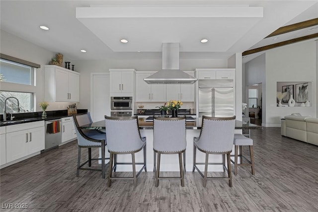 10271 Meridian Hill Ave, Las Vegas, NV 89135 - kitchen with wall chimney range hood, stainless steel appliances, a breakfast bar, dark countertops, and white cabinetry