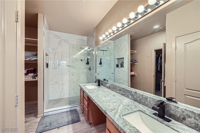 2325 Windmill Pkwy Unit 1622, Henderson, NV 89074 - bathroom with double vanity, a walk in closet, a marble finish shower, and wood finished floors