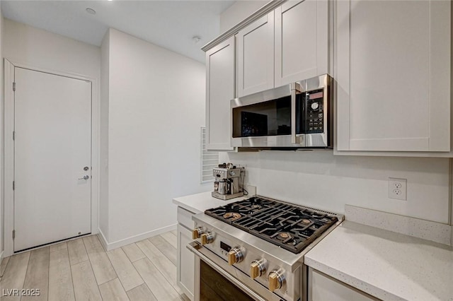 912 Allister Fields Ln, Las Vegas, NV 89138 - kitchen featuring appliances with stainless steel finishes, light wood-style floors, and light stone counters