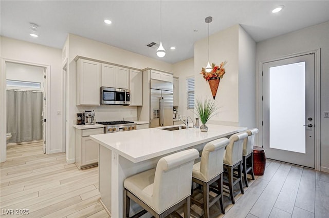 912 Allister Fields Ln, Las Vegas, NV 89138 - kitchen with stainless steel appliances, light wood finished floors, a breakfast bar area, light countertops, and recessed lighting