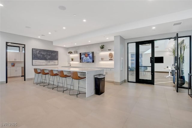 912 Allister Fields Ln, Las Vegas, NV 89138 - kitchen featuring white cabinetry, backsplash, a spacious island, a breakfast bar area, and recessed lighting