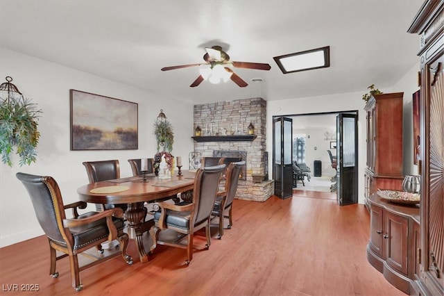 5005 Harmony Ave, Las Vegas, NV 89107 - dining area featuring a ceiling fan, light wood-type flooring, and a stone fireplace