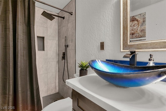 5005 Harmony Ave, Las Vegas, NV 89107 - bathroom with a textured wall, a tile shower, and vanity