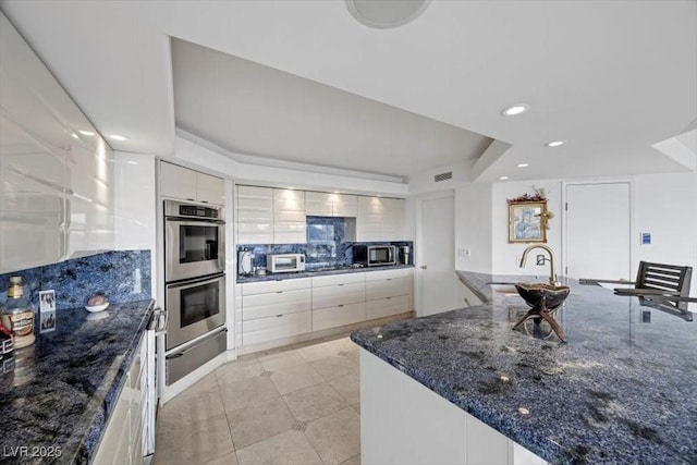 3111 Bel Air Dr Unit 21A & 21C, Las Vegas, NV 89109 - kitchen featuring appliances with stainless steel finishes, a warming drawer, a raised ceiling, backsplash, and recessed lighting