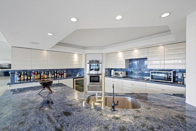 3111 Bel Air Dr Unit 21A & 21C, Las Vegas, NV 89109 - kitchen with stainless steel appliances, beverage cooler, a tray ceiling, backsplash, and recessed lighting