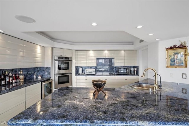 3111 Bel Air Dr Unit 21A & 21C, Las Vegas, NV 89109 - kitchen featuring stainless steel double oven, wine cooler, a raised ceiling, tasteful backsplash, and modern cabinets