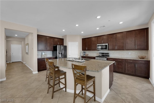 2714 Frabiele St, Henderson, NV 89044 - kitchen with stainless steel appliances, backsplash, light tile patterned floors, a breakfast bar, and recessed lighting