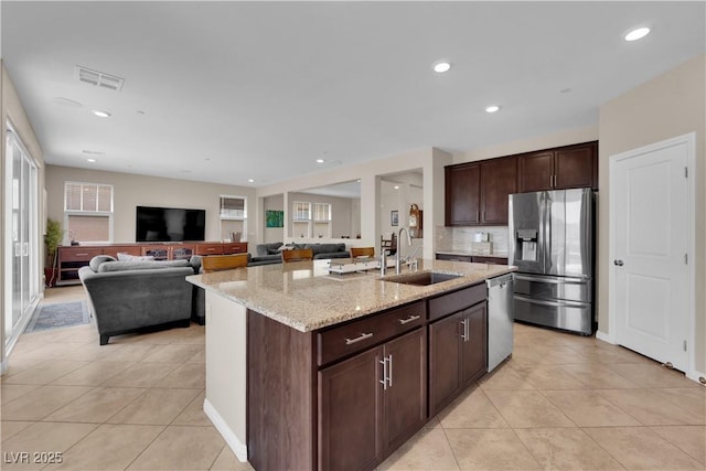 2714 Frabiele St, Henderson, NV 89044 - kitchen with stainless steel appliances, light stone counters, light tile patterned floors, a center island with sink, and recessed lighting