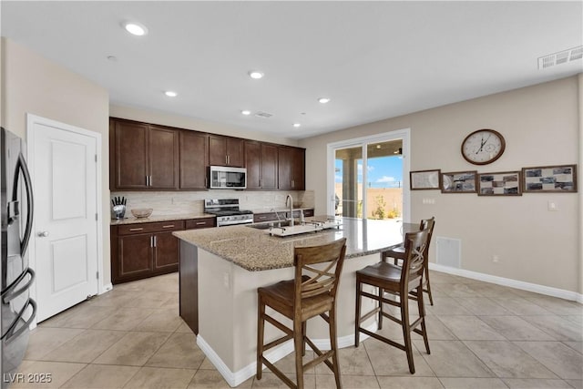 2714 Frabiele St, Henderson, NV 89044 - kitchen featuring stainless steel appliances, light tile patterned floors, a kitchen breakfast bar, light stone countertops, and recessed lighting