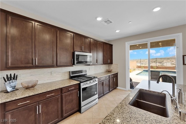 2714 Frabiele St, Henderson, NV 89044 - kitchen with stainless steel appliances, decorative backsplash, light stone counters, light tile patterned floors, and recessed lighting