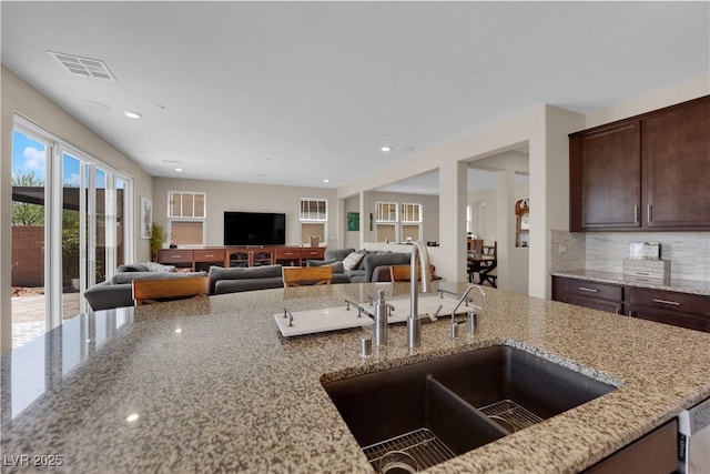2714 Frabiele St, Henderson, NV 89044 - kitchen featuring light stone countertops, dark brown cabinetry, decorative backsplash, recessed lighting, and open floor plan