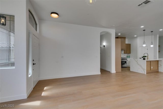 10452 Niagara Falls Ln, Las Vegas, NV 89144 - unfurnished living room with light wood-style floors, arched walkways, and recessed lighting