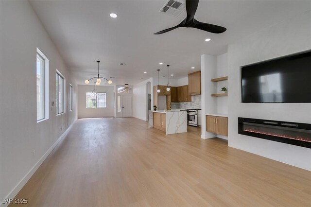 10452 Niagara Falls Ln, Las Vegas, NV 89144 - unfurnished living room featuring light wood-type flooring, ceiling fan, recessed lighting, and a glass covered fireplace