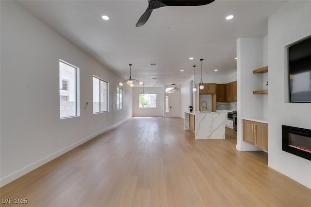 10452 Niagara Falls Ln, Las Vegas, NV 89144 - unfurnished living room with a ceiling fan, recessed lighting, light wood-style floors, and a glass covered fireplace
