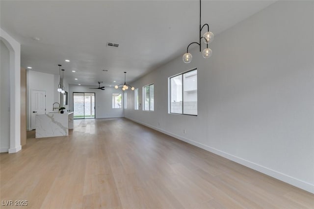 10452 Niagara Falls Ln, Las Vegas, NV 89144 - unfurnished living room featuring light wood-type flooring, a ceiling fan, recessed lighting, and arched walkways