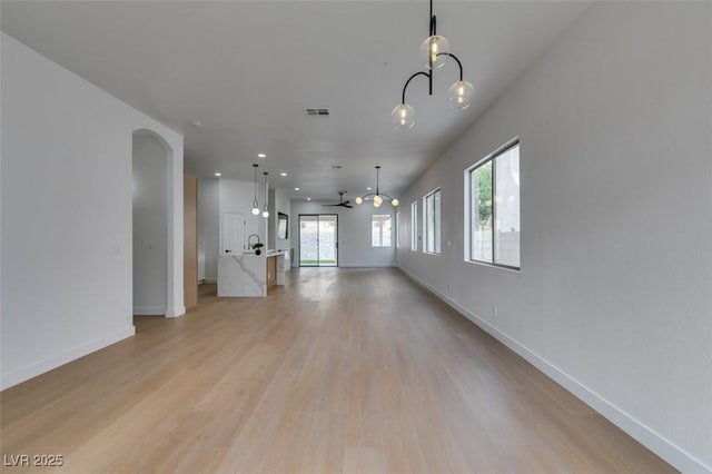 10452 Niagara Falls Ln, Las Vegas, NV 89144 - unfurnished living room with plenty of natural light, light wood-type flooring, a chandelier, arched walkways, and recessed lighting
