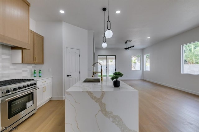 10452 Niagara Falls Ln, Las Vegas, NV 89144 - kitchen with stainless steel stove, light wood-style flooring, open floor plan, backsplash, and recessed lighting