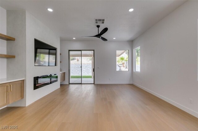 10452 Niagara Falls Ln, Las Vegas, NV 89144 - unfurnished living room with a ceiling fan, plenty of natural light, recessed lighting, light wood-style floors, and a glass covered fireplace