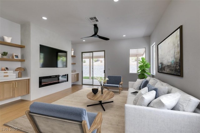 10452 Niagara Falls Ln, Las Vegas, NV 89144 - living room featuring recessed lighting, a ceiling fan, light wood finished floors, and a glass covered fireplace