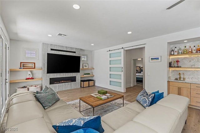 712 Proud Eagle Ln, Las Vegas, NV 89144 - living area featuring light wood-type flooring, a barn door, wet bar, a large fireplace, and recessed lighting