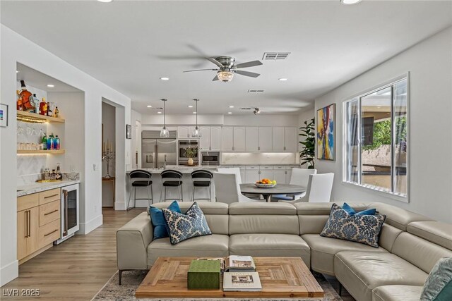 712 Proud Eagle Ln, Las Vegas, NV 89144 - living area with wine cooler, bar with sink, a ceiling fan, recessed lighting, and light wood finished floors