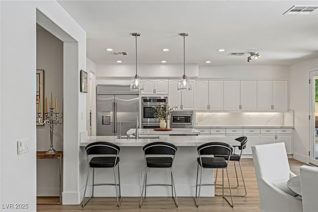 712 Proud Eagle Ln, Las Vegas, NV 89144 - kitchen featuring built in appliances, light wood-type flooring, a kitchen bar, white cabinets, and recessed lighting