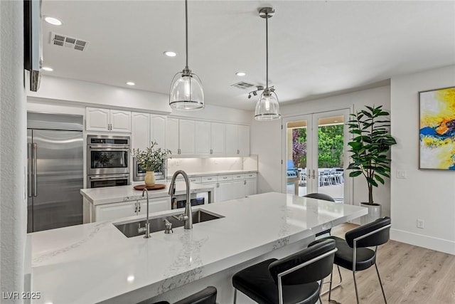 712 Proud Eagle Ln, Las Vegas, NV 89144 - kitchen with appliances with stainless steel finishes, white cabinetry, recessed lighting, light wood-type flooring, and a kitchen bar