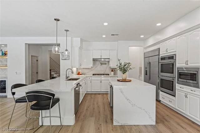 712 Proud Eagle Ln, Las Vegas, NV 89144 - kitchen featuring built in appliances, a peninsula, a kitchen breakfast bar, white cabinets, and recessed lighting