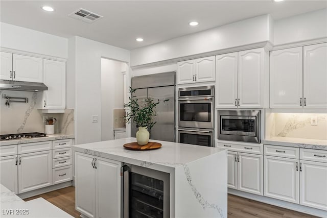 712 Proud Eagle Ln, Las Vegas, NV 89144 - kitchen featuring wine cooler, built in appliances, wood finished floors, under cabinet range hood, and white cabinetry