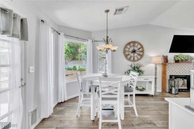 6536 Pleasant Plains Way, Las Vegas, NV 89108 - dining space with a chandelier, light wood-style floors, and a brick fireplace