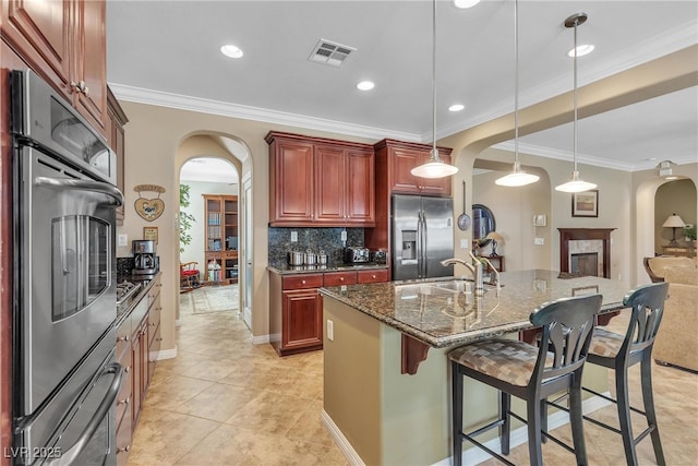 4408 Oasis Plains Ave, North Las Vegas, NV 89085 - kitchen with stainless steel appliances, arched walkways, reddish brown cabinets, crown molding, and tasteful backsplash