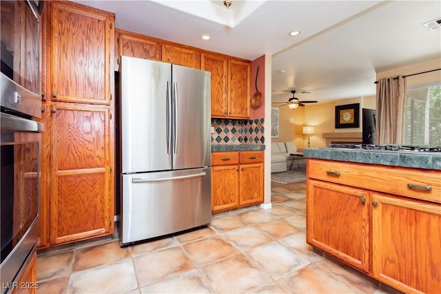 8875 Tidal Bay Dr, Las Vegas, NV 89117 - kitchen featuring freestanding refrigerator, gas stovetop, brown cabinets, decorative backsplash, and dark countertops