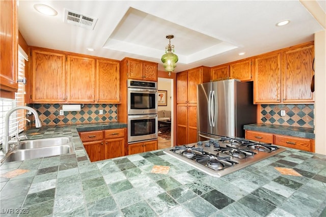 8875 Tidal Bay Dr, Las Vegas, NV 89117 - kitchen featuring appliances with stainless steel finishes, a tray ceiling, backsplash, recessed lighting, and brown cabinets