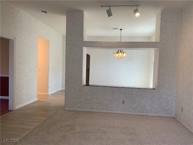 6704 Lost River Ct, Las Vegas, NV 89108 - spare room featuring a chandelier, wood finished floors, rail lighting, carpet floors, and wallpapered walls
